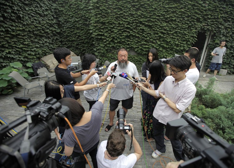 Image: Chinese dissident artist Ai Weiwei holds up his phone on speaker as he and journalists listen to the verdict of his court hearing at the courtyard of his studio in Beijing